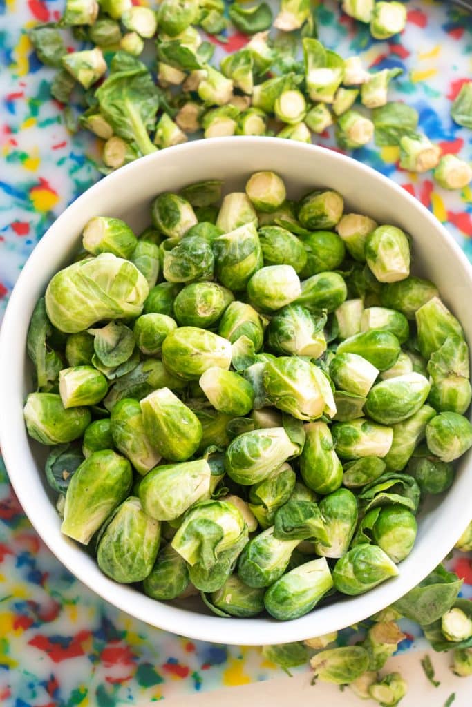 brussels sprouts with ends trimmed off in white bowl. 