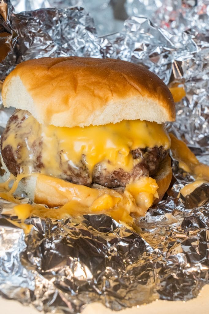 Cheeseburger cooked in the oven wrapped in aluminum foil. 