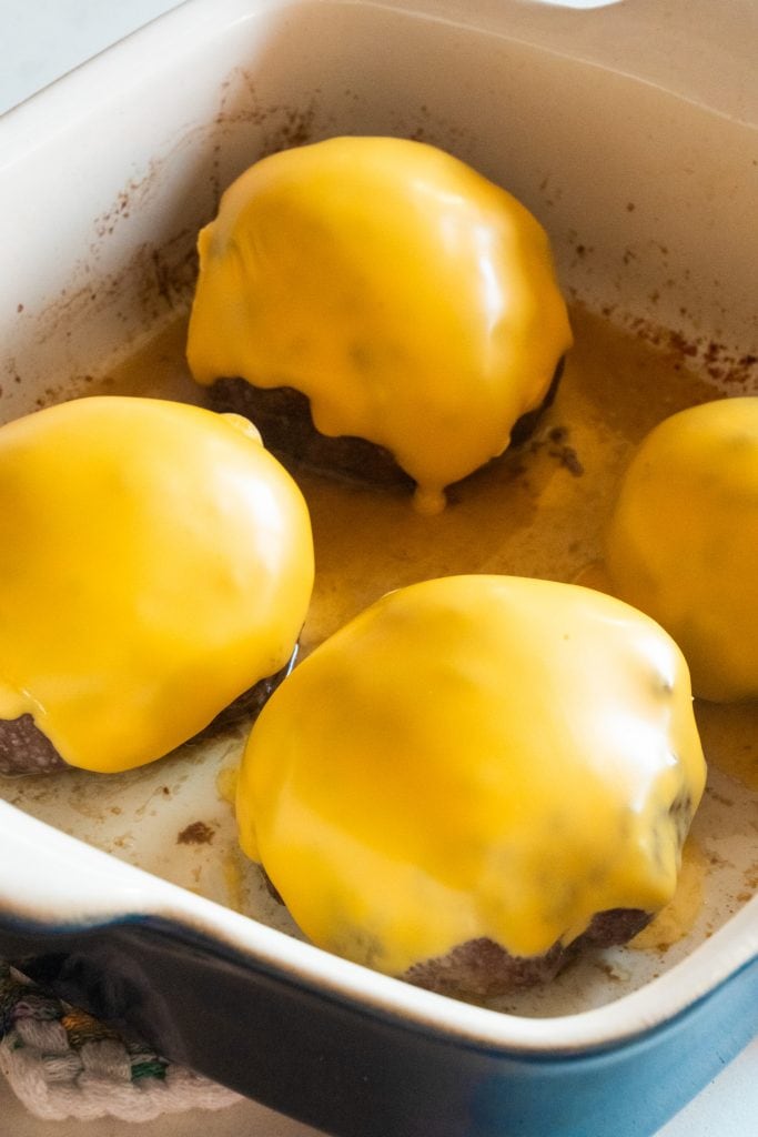 cheese melted on top of burgers in baking dish.