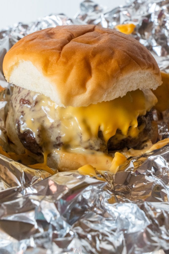 juicy burger with melted cheese on foil. 