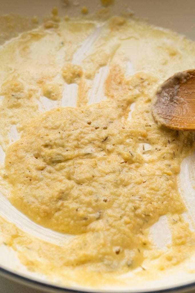 spoon stirring cream sauce in pan.