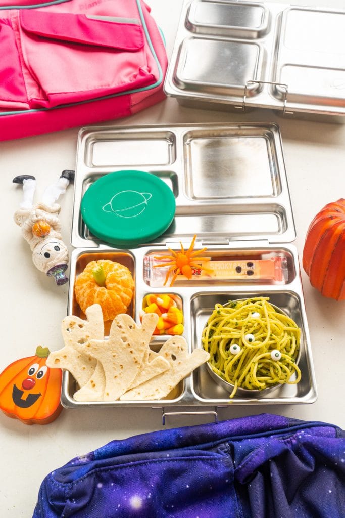 lunch box on table with halloween decorations filled with halloween inspired food for kids.