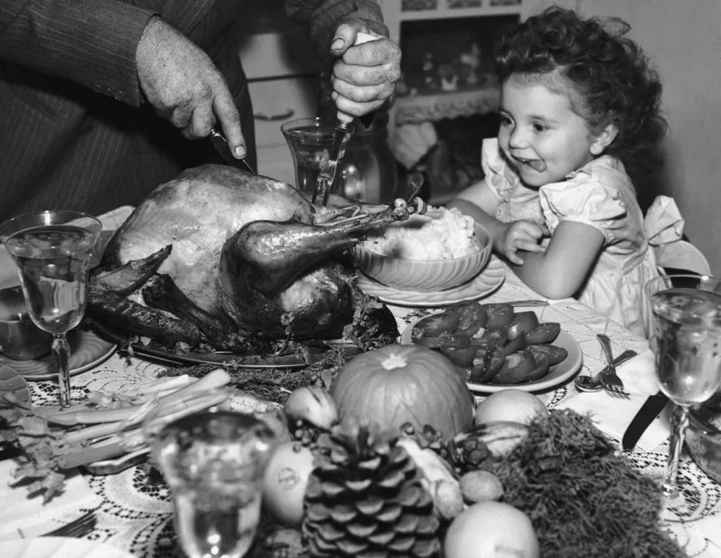 vintage photo of little girl at thanksgiving table with turkey in front of her. 