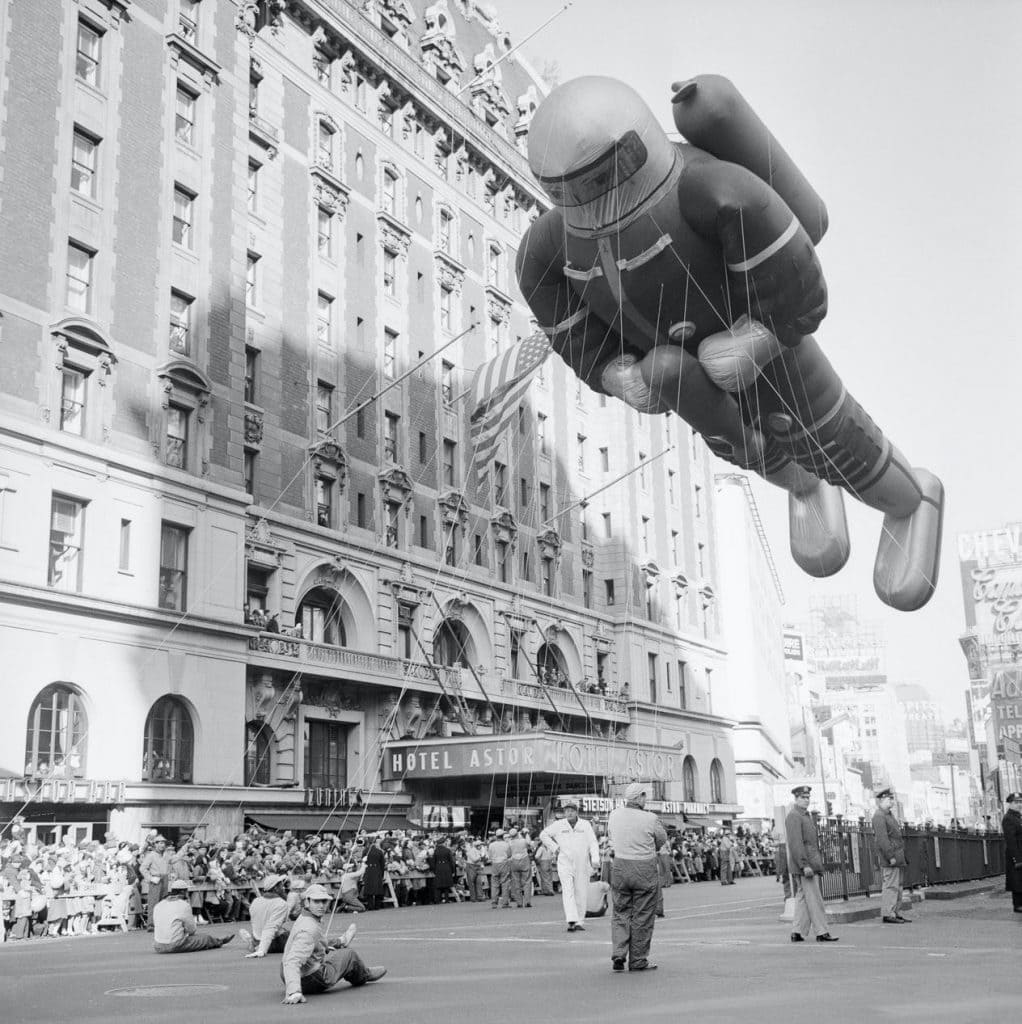 vintage photo of macy's thanksgiving parade with astronaut balloon in the sky.