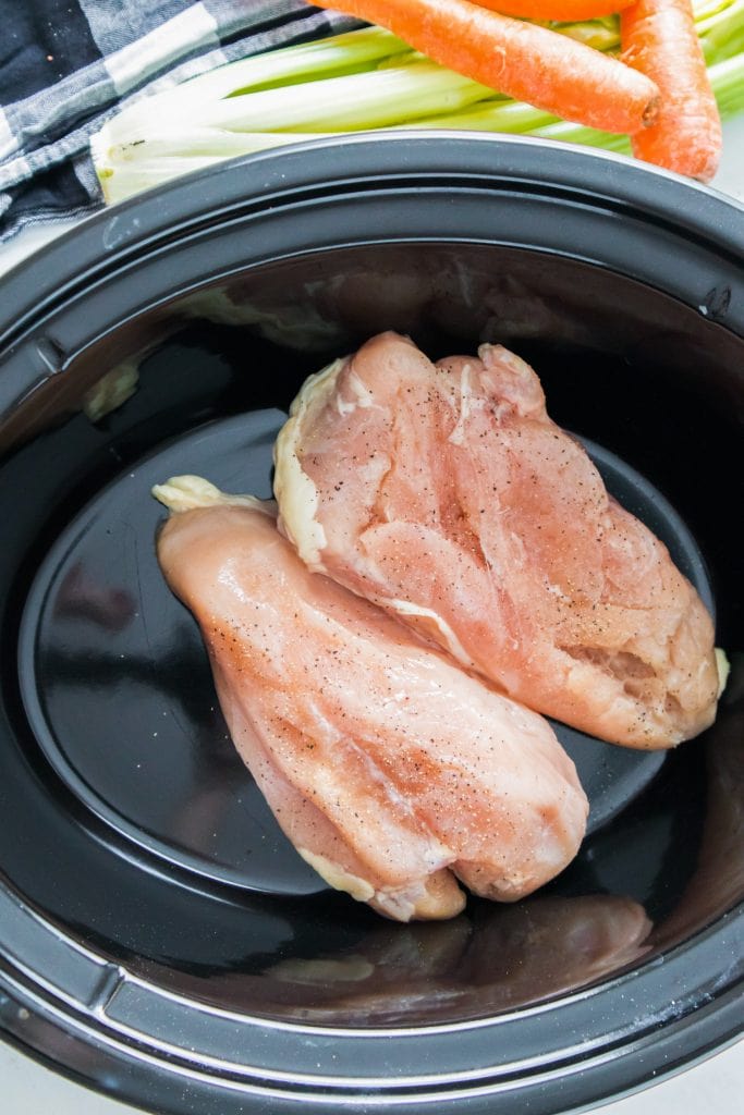 chicken breast seasoned with salt and pepper in slow cooker.