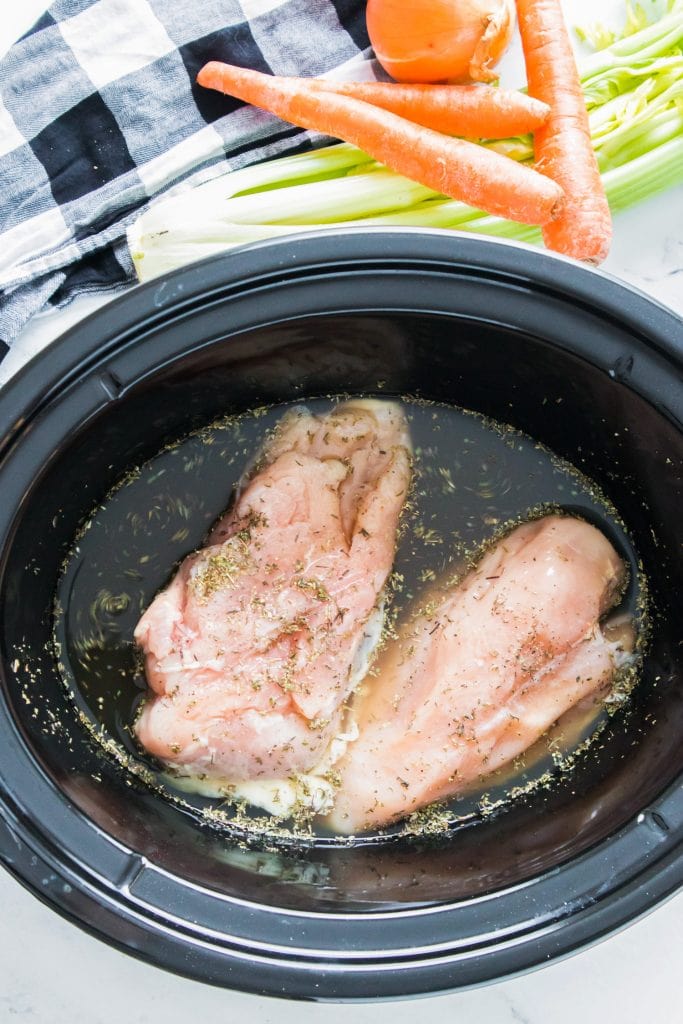 broth and spices added to slow cooker with chicken.