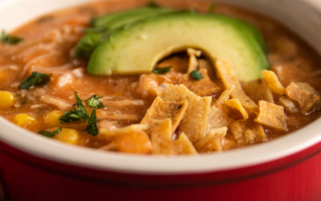 chicken tortilla soup in red bowl.