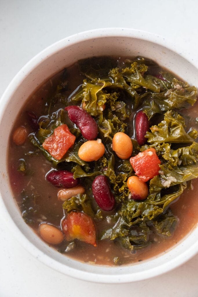 bean soup with kale in broth in white bowl.