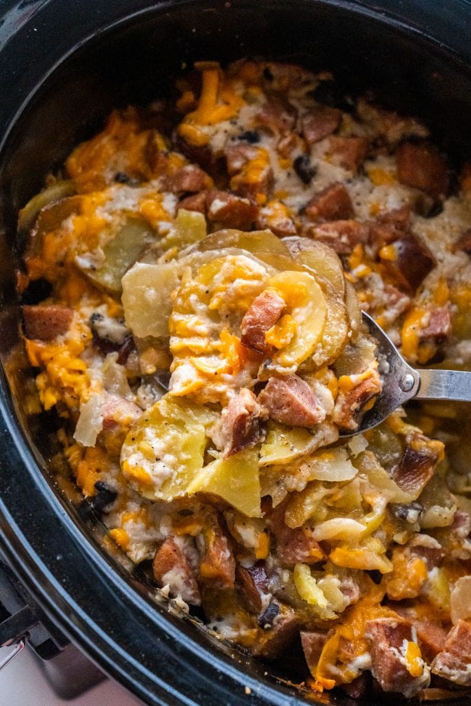 spoon filled with potatoes over top of slow cooker.