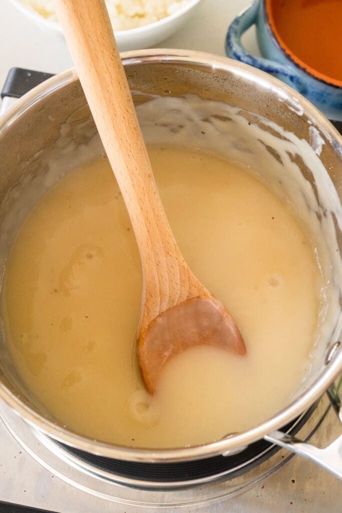 homemade chicken gravy in saucepan on burner.