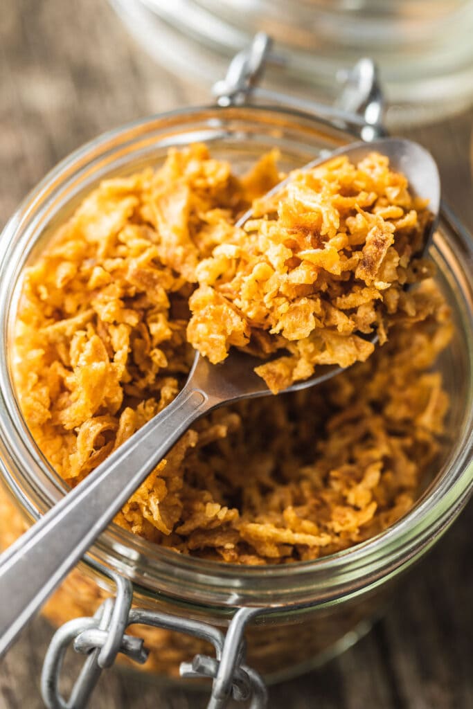 spoon lifting out fried onions out of jar.