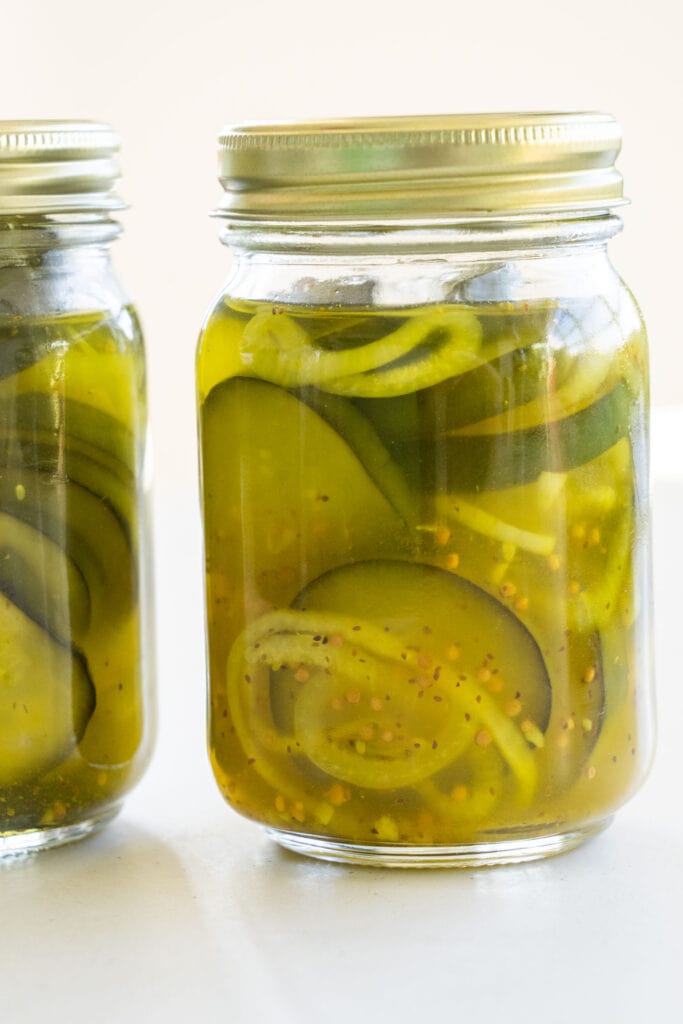 fresh pickles in pint mason jar on table.