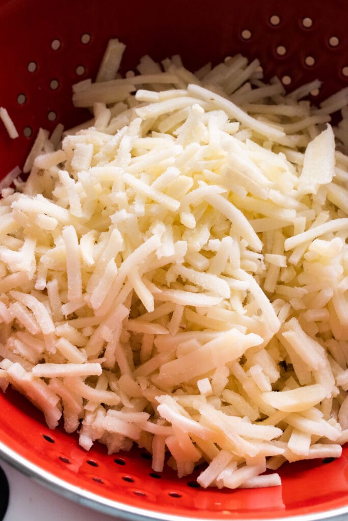 defrosted hash browns in strainer.