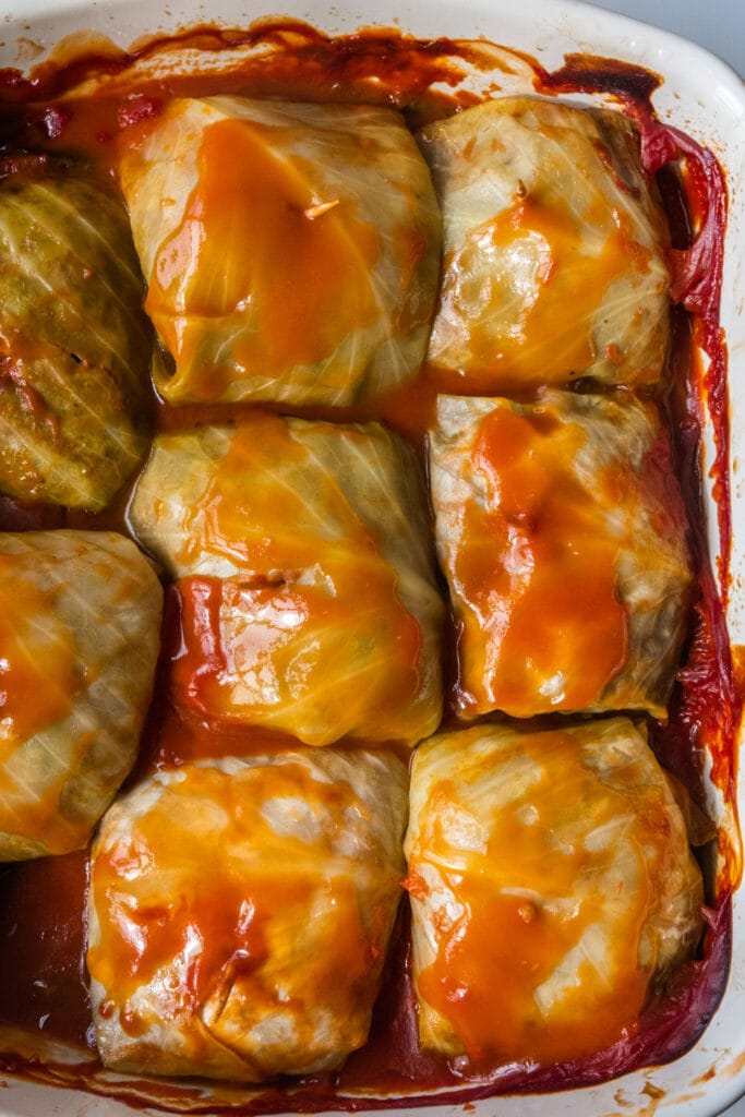 polish cabbage rolls in baking dish with tomato sauce on top.