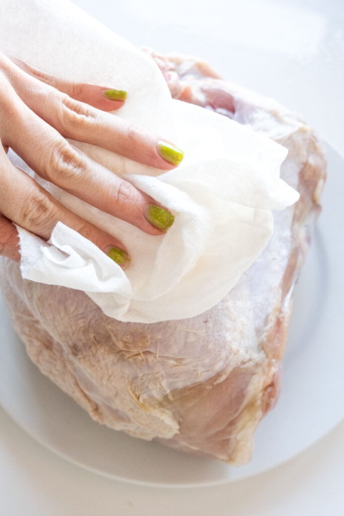 hand patting turkey breast down.