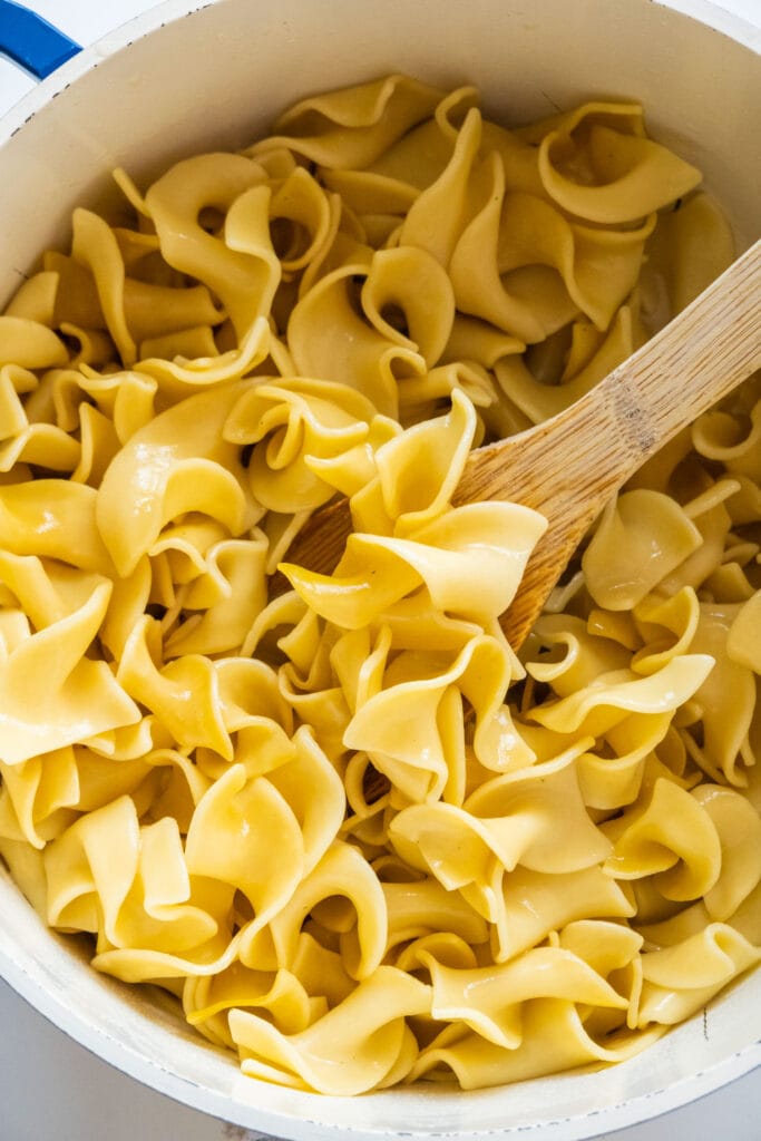 spoon stirring buttery egg noodles.
