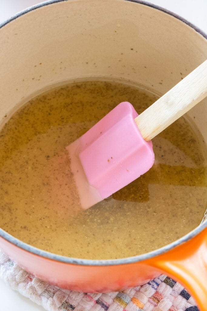 salad dressing being made in saucepan with spoon stirring it.