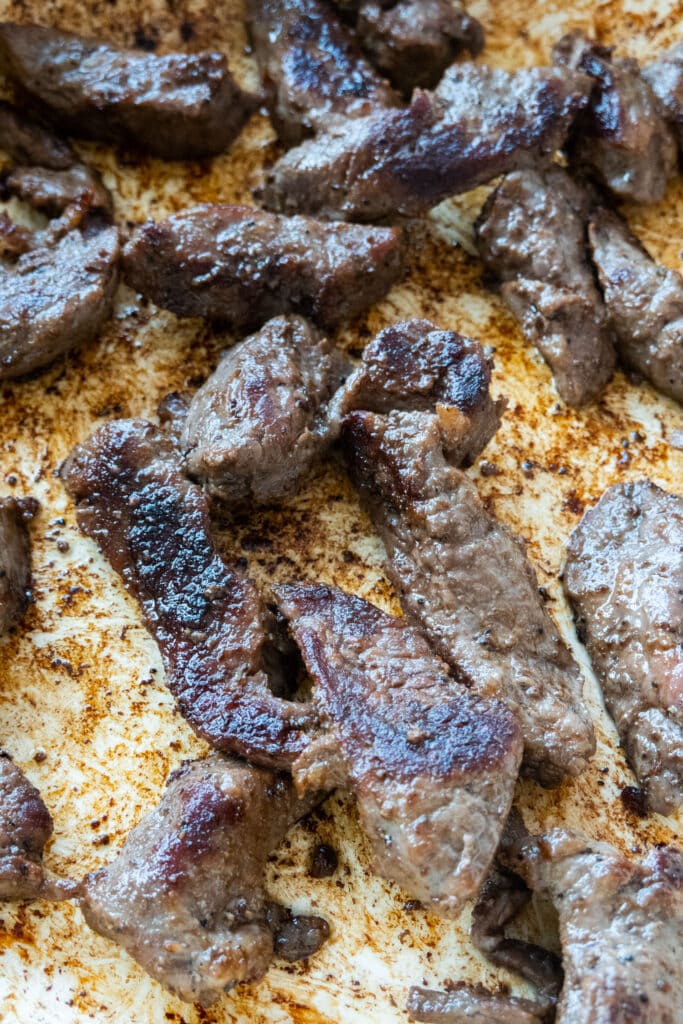 browned beef slices in frying pan.