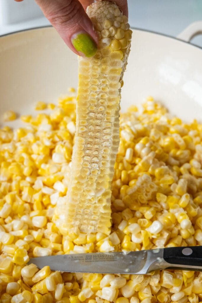 corn cob that has had kernels cut off it, with knife laying close by.