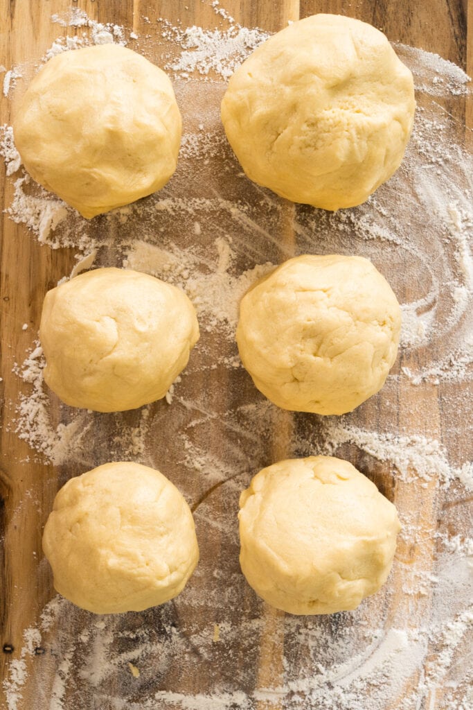 6 balls of dough on cutting board.