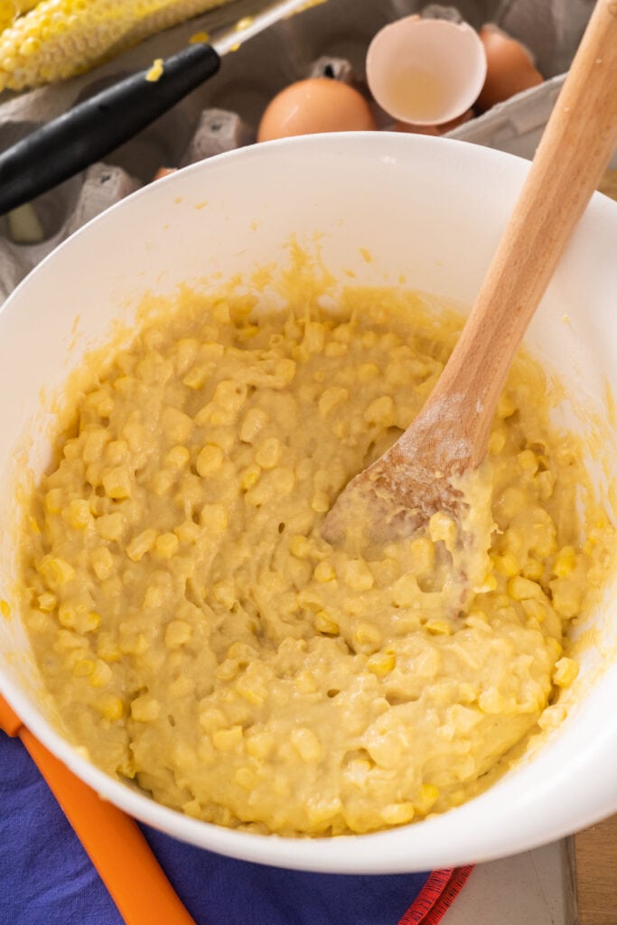corn added into pancake batter in bowl. 