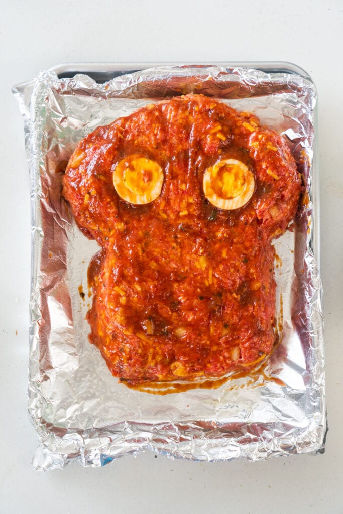 uncooked meatloaf with tomato sauce glaze on top of it.