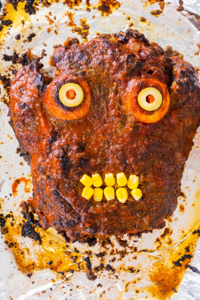 meatloaf shaped like a zombie face on baking sheet.