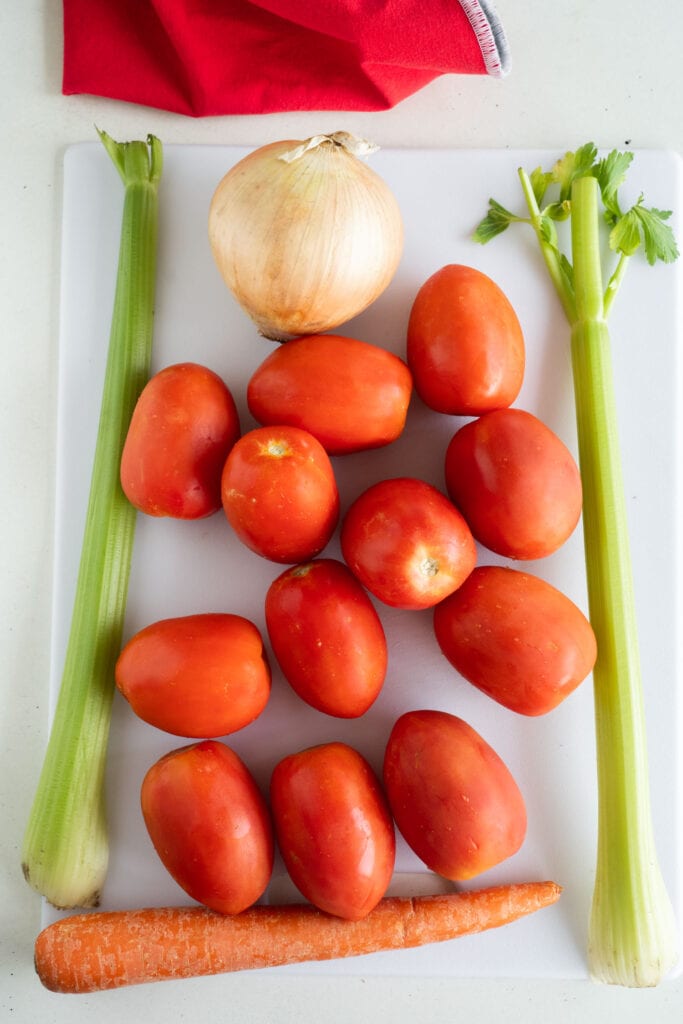 Tomatoes, celery and onion on cutting board.