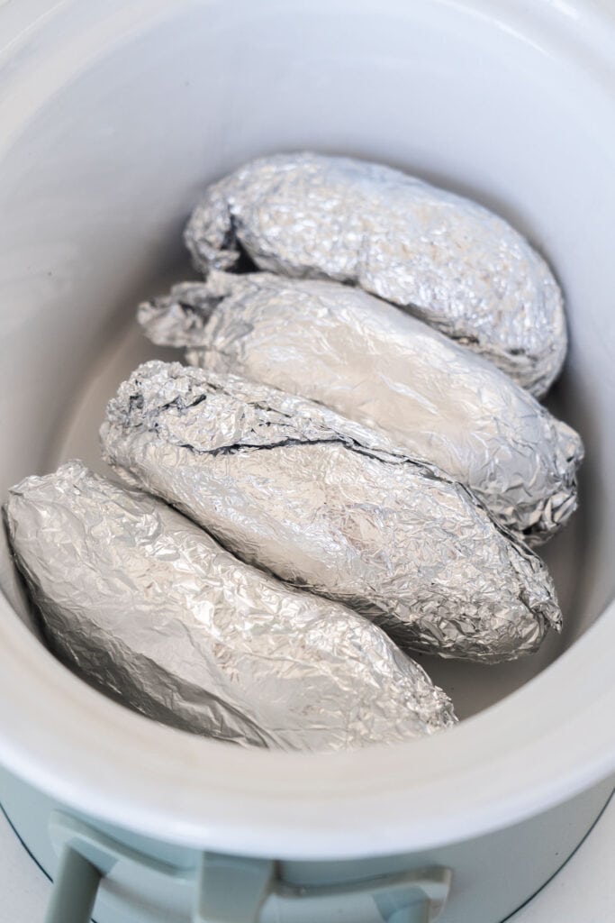potatoes wrapped in aluminum foil in slow cooker.