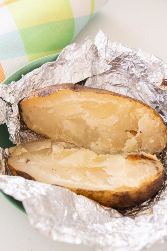 baked potato open in aluminum foil showing how soft they are inside.