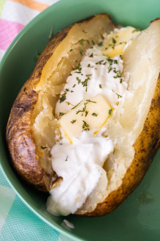 closeup of baked potato with butter and sour cream.