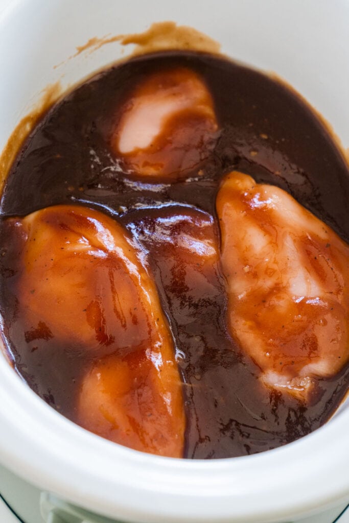 chicken breasts covered in sauce in slow cooker.