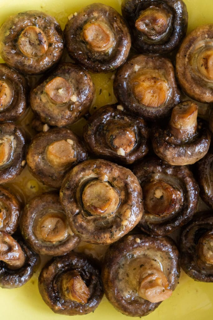 closeup of lots of cooked mushrooms in yellow bowl. 