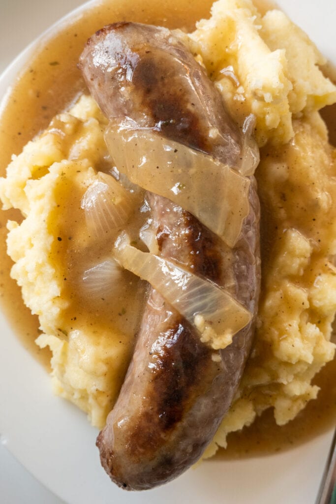 closeup of bangers and mash with gravy on top.