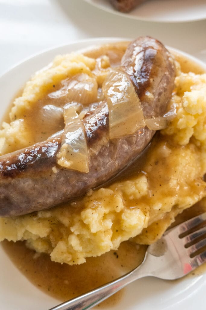 bangers and mash on white plate on table.