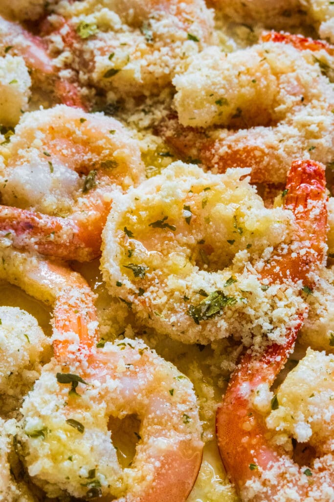 butter being poured on top of shrimp in baking dish.