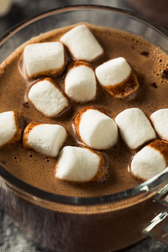 closeup of creamy hot chocolate in glass with mini marshmallows.