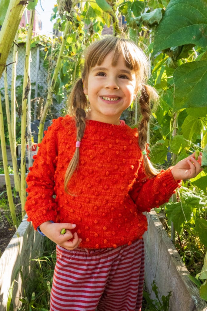 little girl eating green beans in garden
