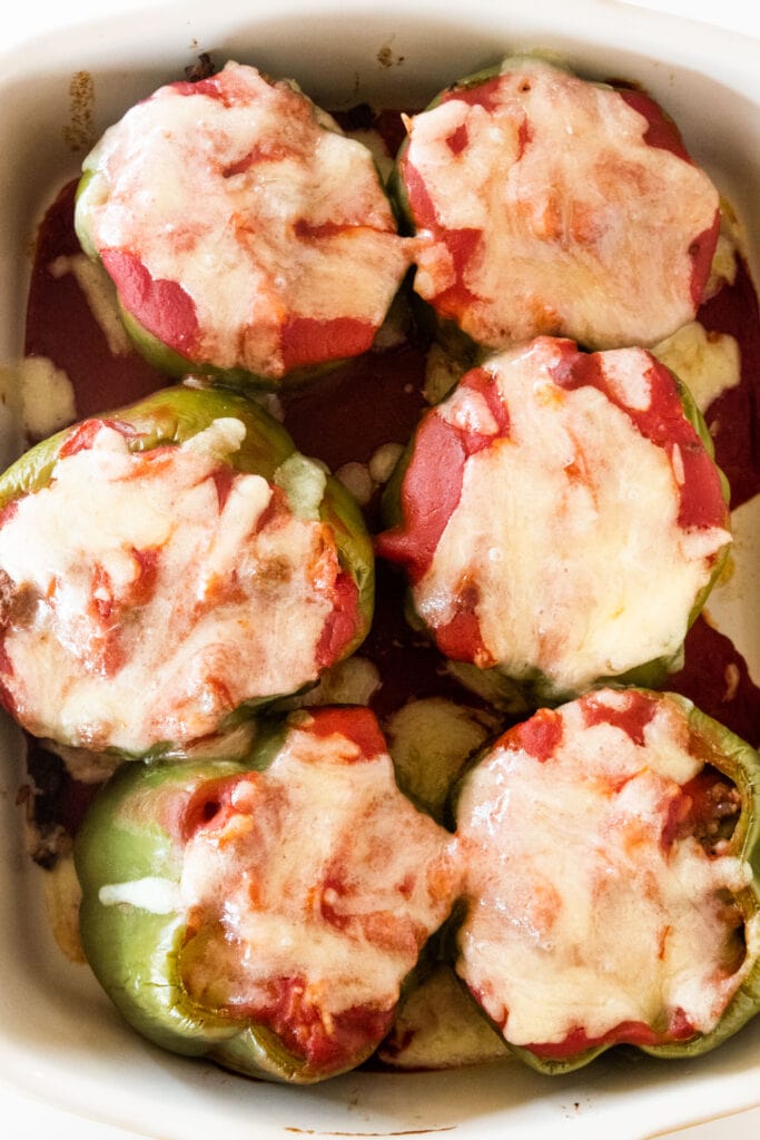 baked stuffed peppers in baking dish with melted cheese on top.