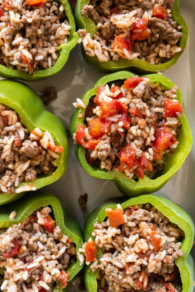 peppers filled with ground beef mixture in baking dish.