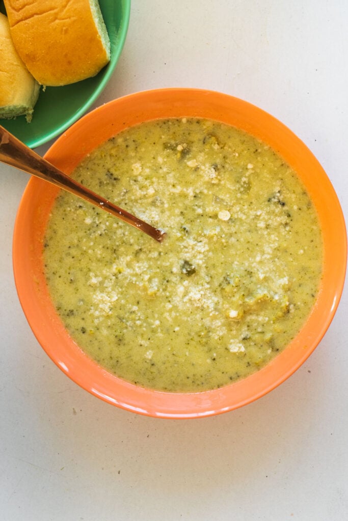 broccoli soup with spoon in orange bowl.