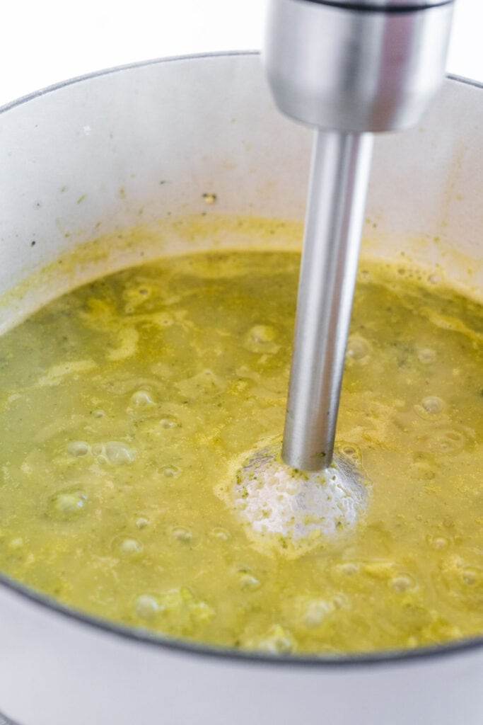 immersion blender blending soup in pot.