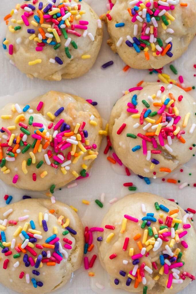rainbow sprinkles on ricotta cookies on parchment paper.