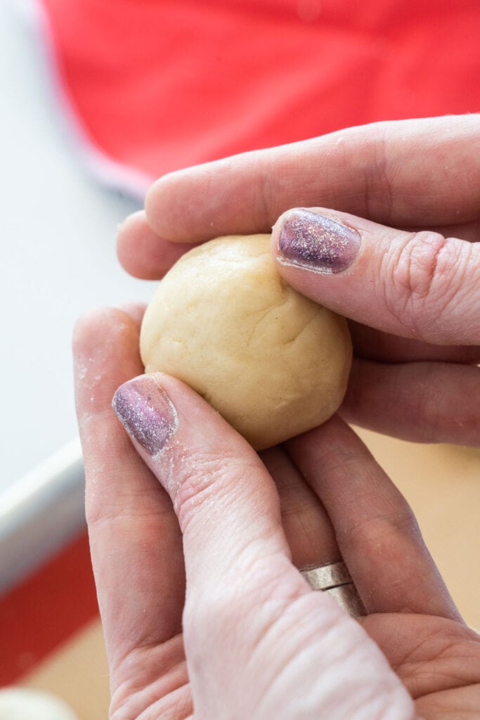 cookie dough ball being rolled in hands.