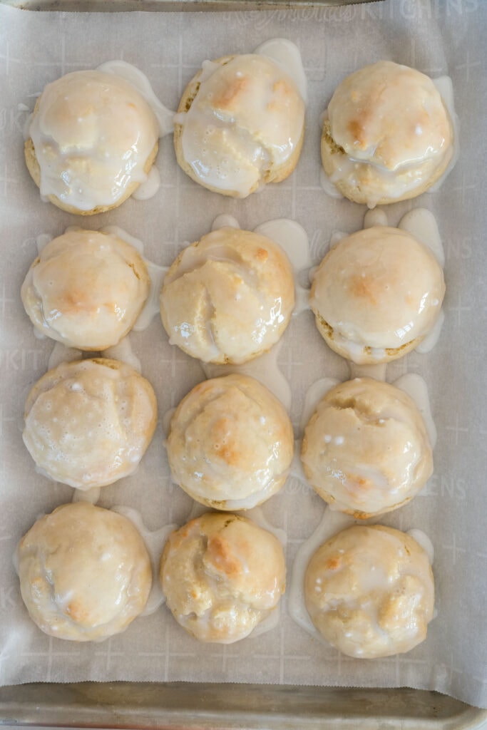 glaze on top of ricotta cookies on parchment paper.
