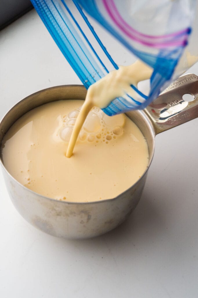 frozen evaporated milk being poured into measuring cup.