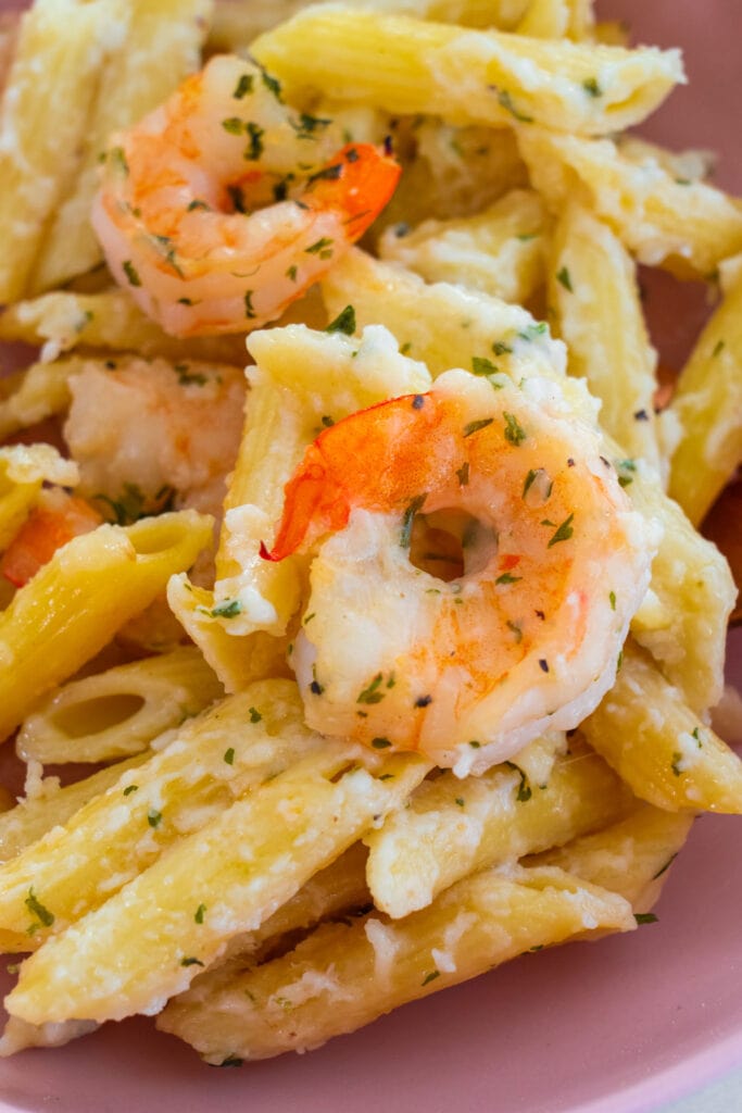 closeup of shrimp and pasta on pink plate.