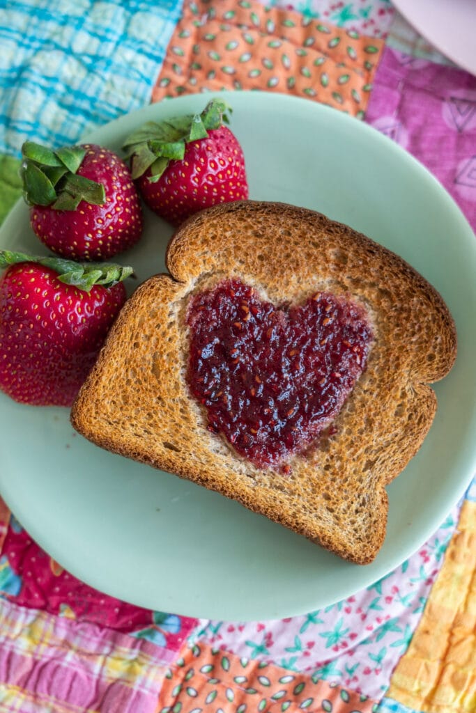 raspberry jam heart toast on green plate.