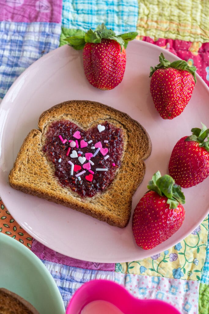 sprinkles toast on pink plate with strawberries.