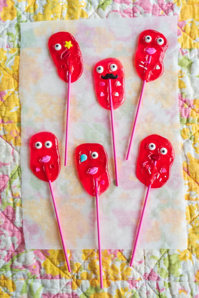red lollipops with faces and sprinkles on them.